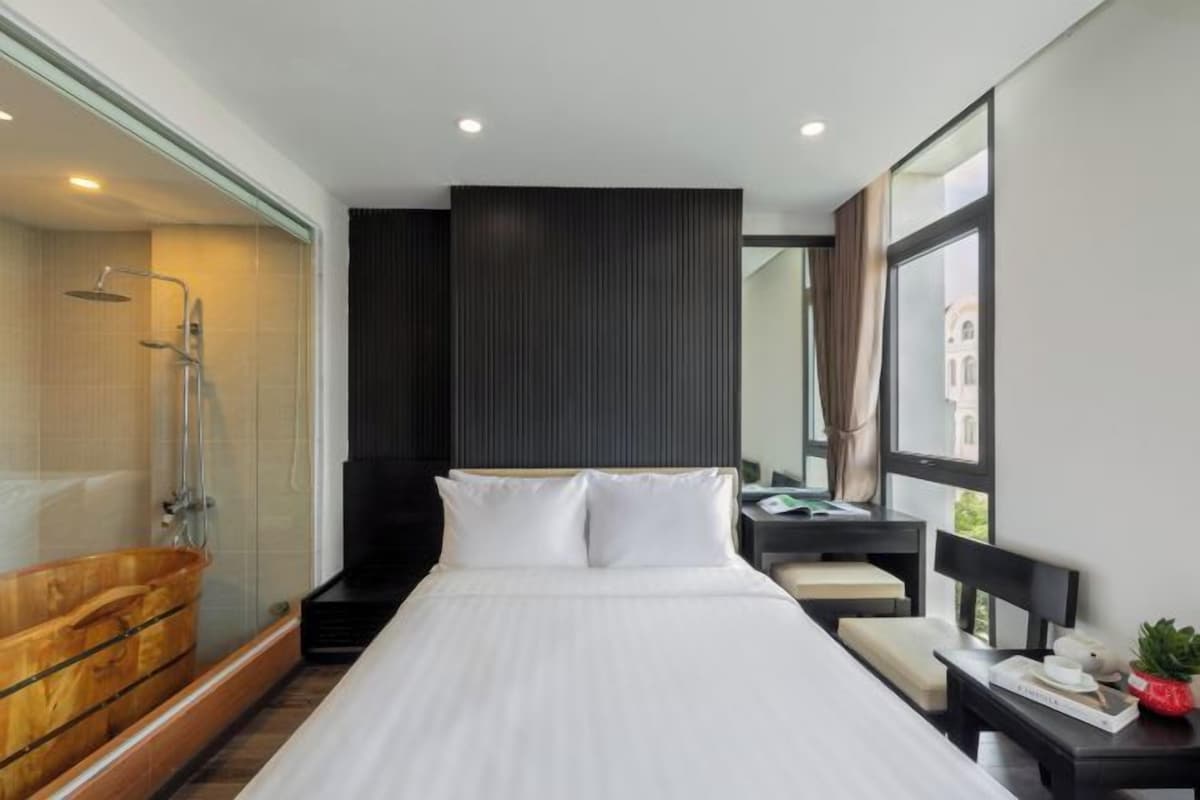 Una habitación de hotel moderna con una cama grande, una bañera de madera, una ducha y un escritorio con una silla.