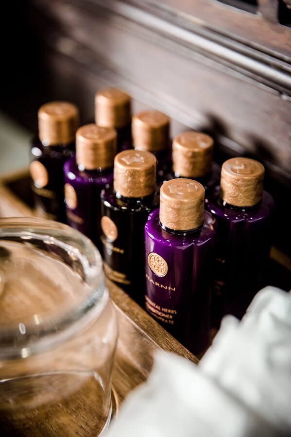 Un plateau en bois contenant plusieurs flacons de liquide, qui pourraient contenir des huiles essentielles ou des parfums, ainsi qu'un bocal en verre.