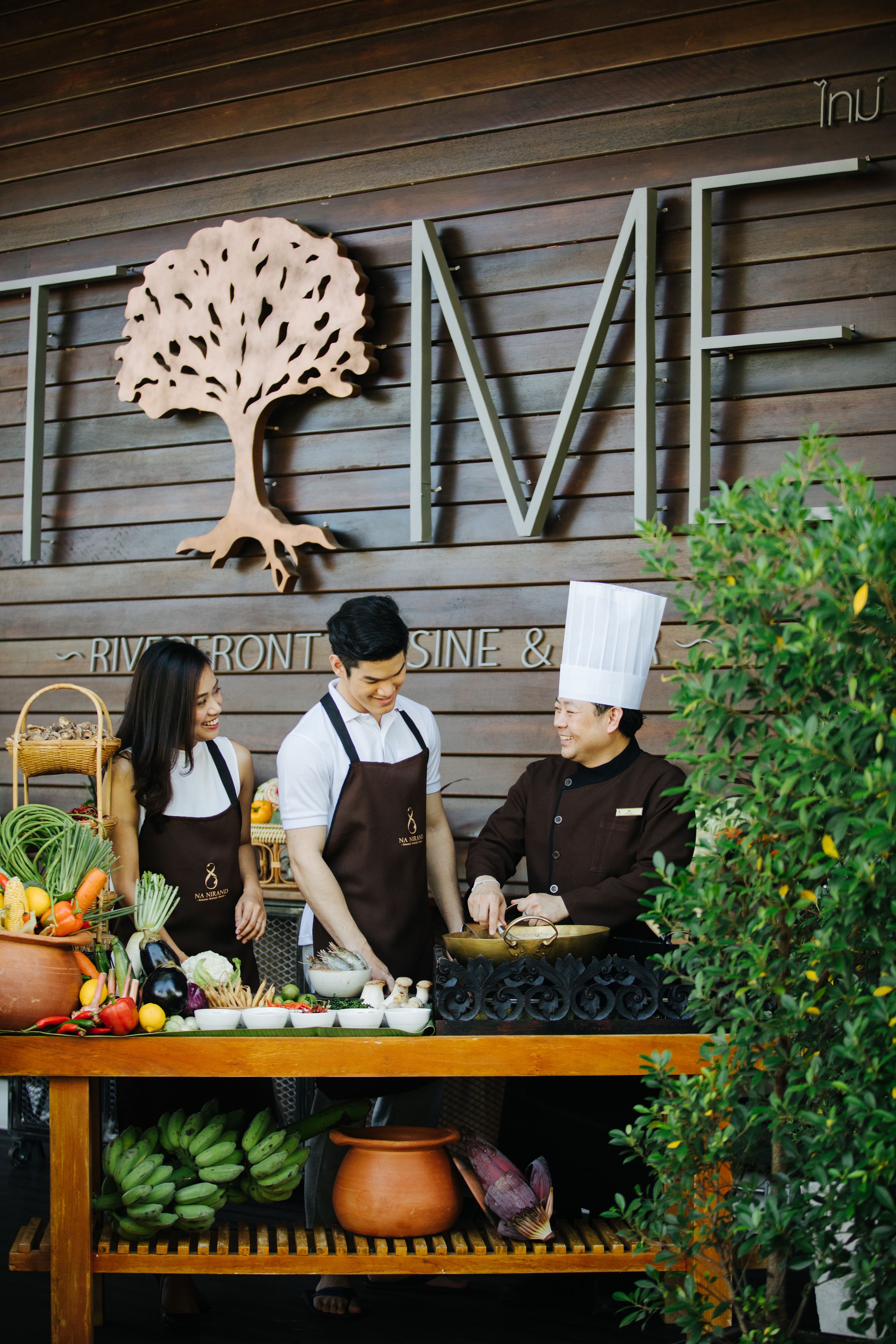 Una encimera de cocina con chefs preparando comida, rodeada de productos frescos y utensilios de cocina.