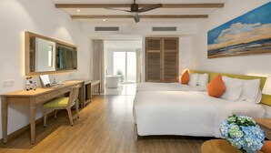 A modern hotel room with a wooden desk, a bed with white bedding, a large mirror, and a painting of a sunset. - Risemount Premier Resort Da Nang (Da Nang)