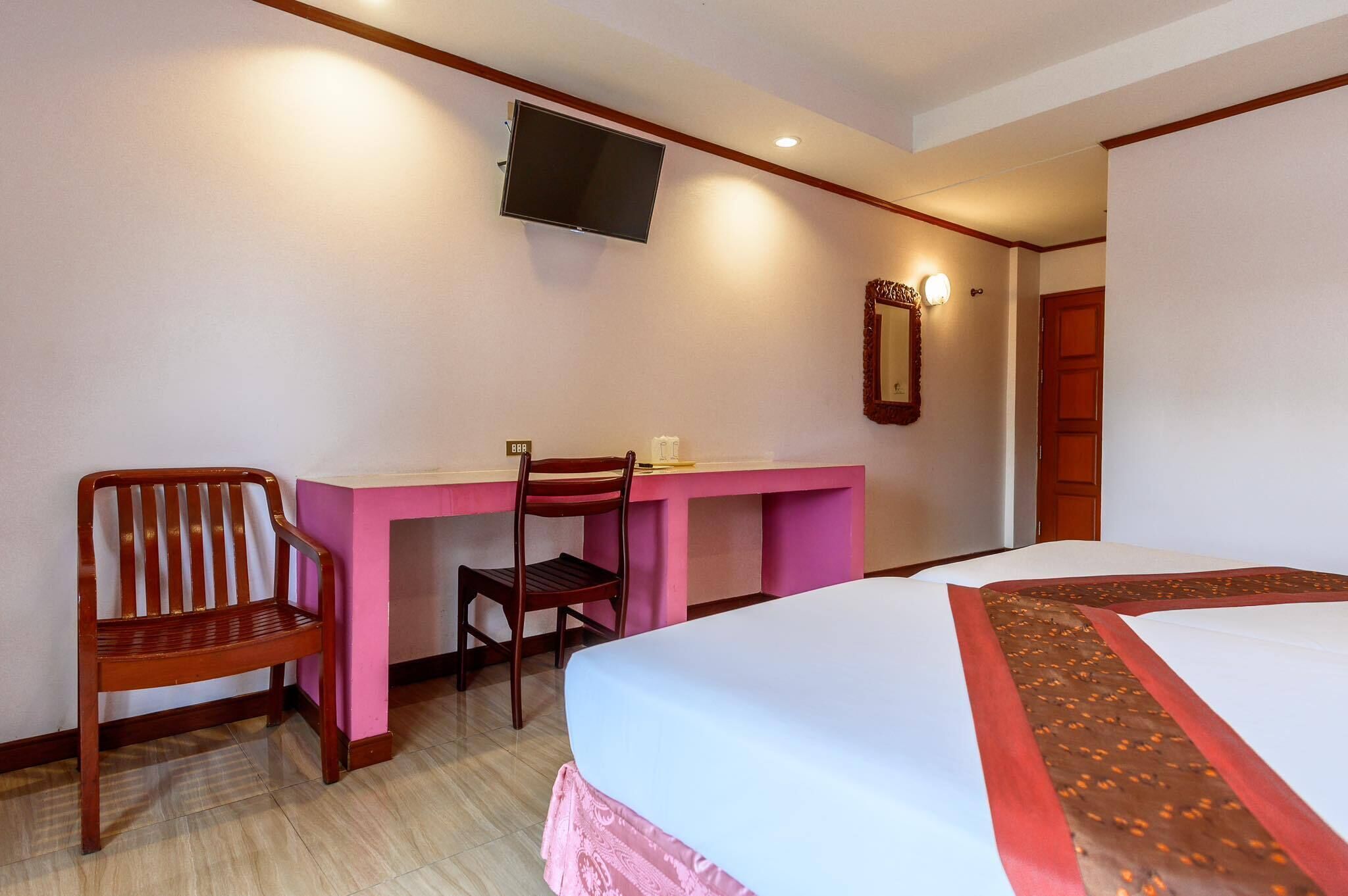 A hotel room with a bed, a desk, a chair, a television, and a mirror.