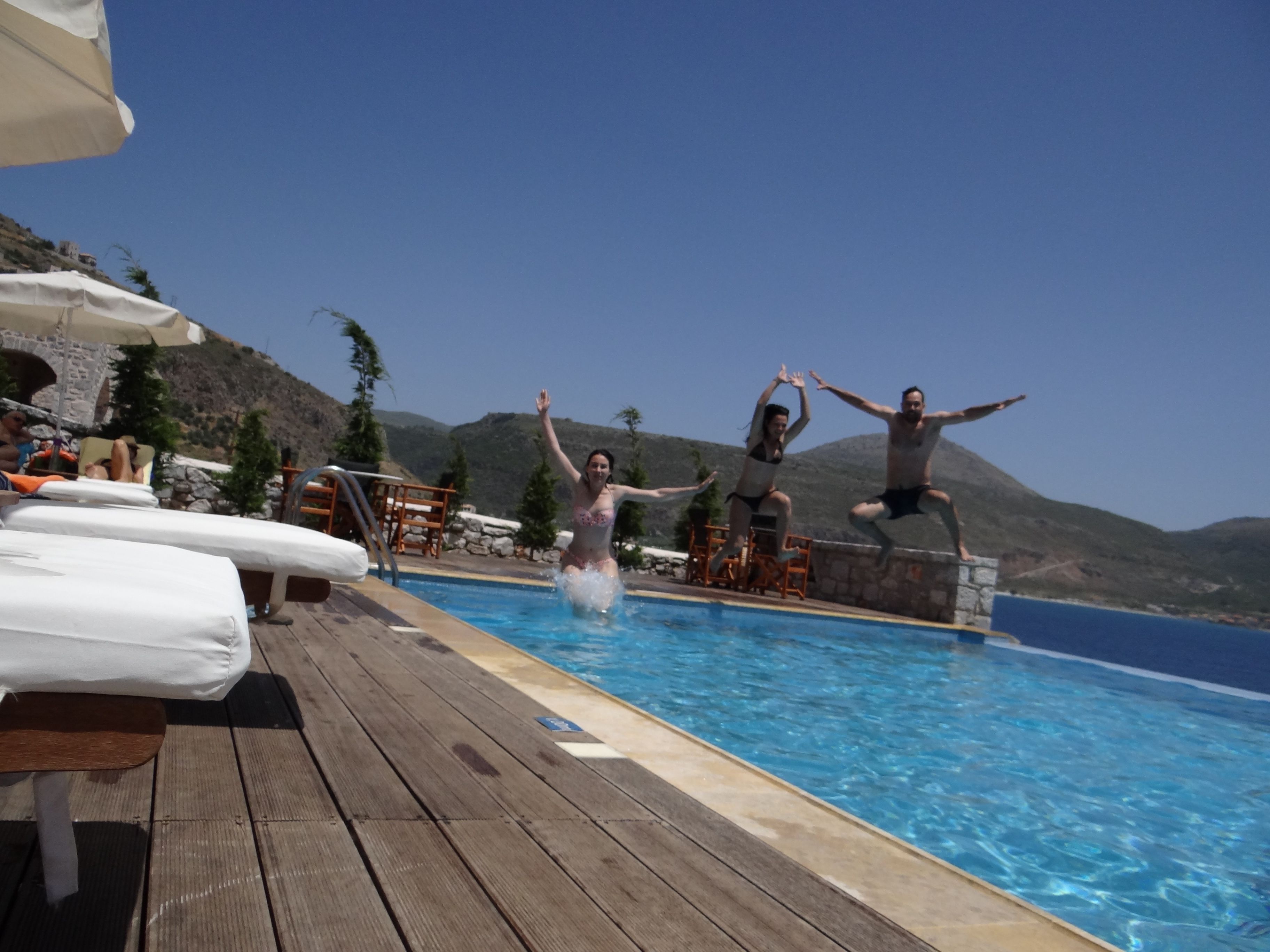 Eine Holzterrasse mit Liegestühlen und einem Pool.
