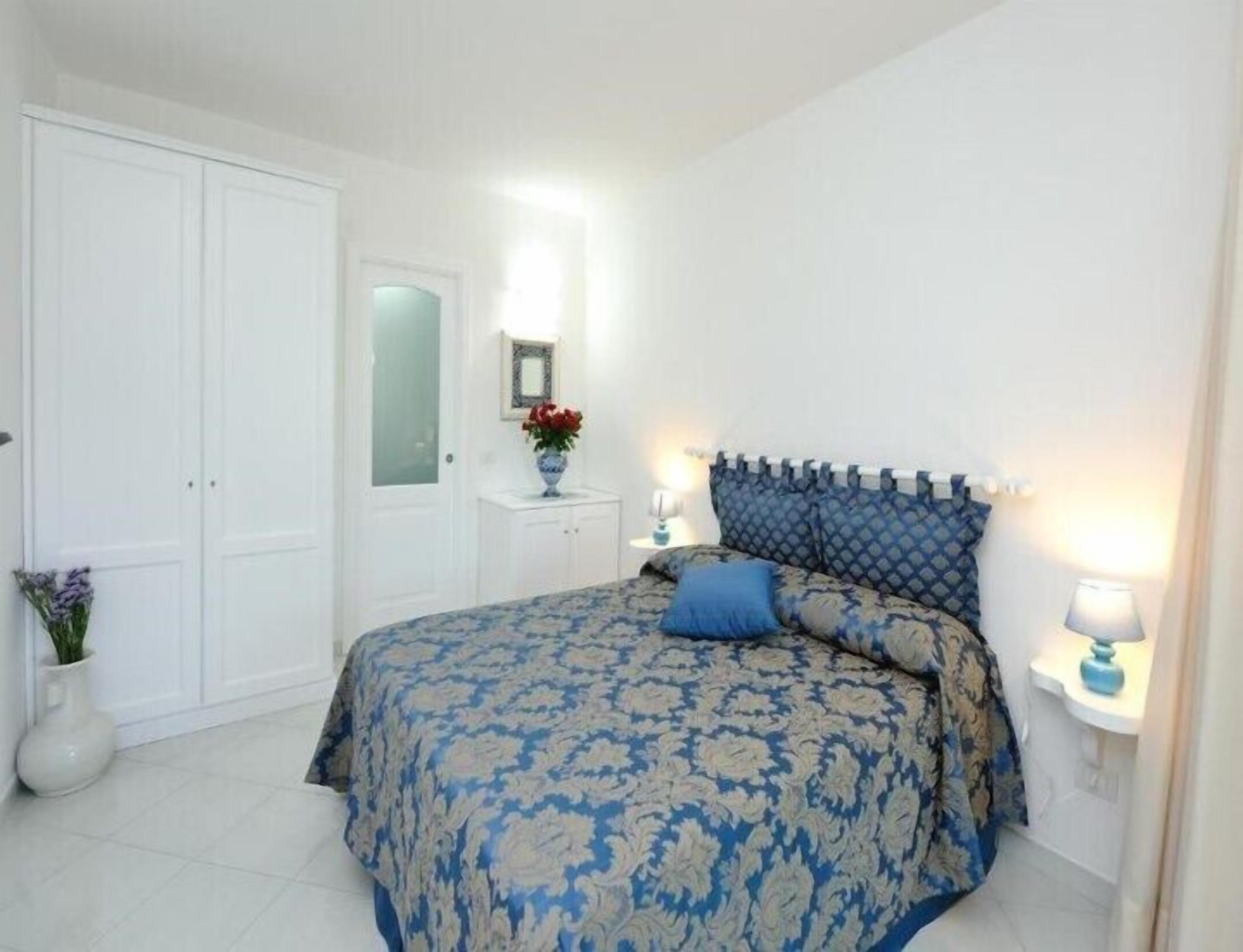 Un dormitorio con una cama, una mesita de noche, un aparador y una puerta.