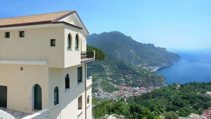 A coastal building with a balcony overlooking a mountainous landscape and the sea. - La Dolce Vita Ravello (Ravello)