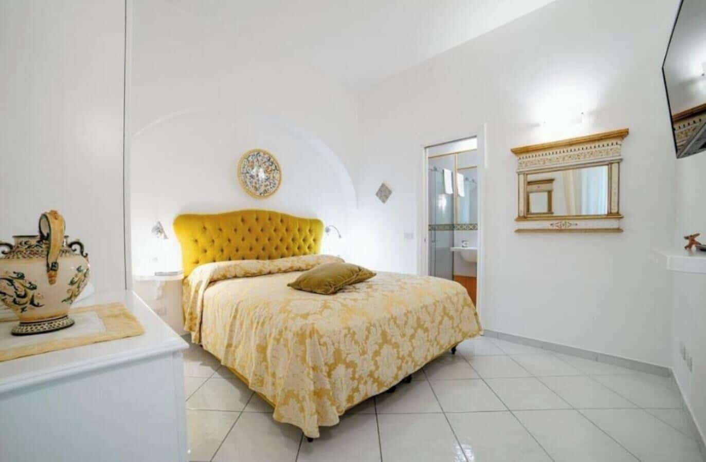 A bedroom with a large bed, a bedside table, and a decorative vase.