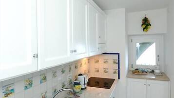 A modern kitchen with white cabinets, a stainless steel sink, and a window above the sink.
