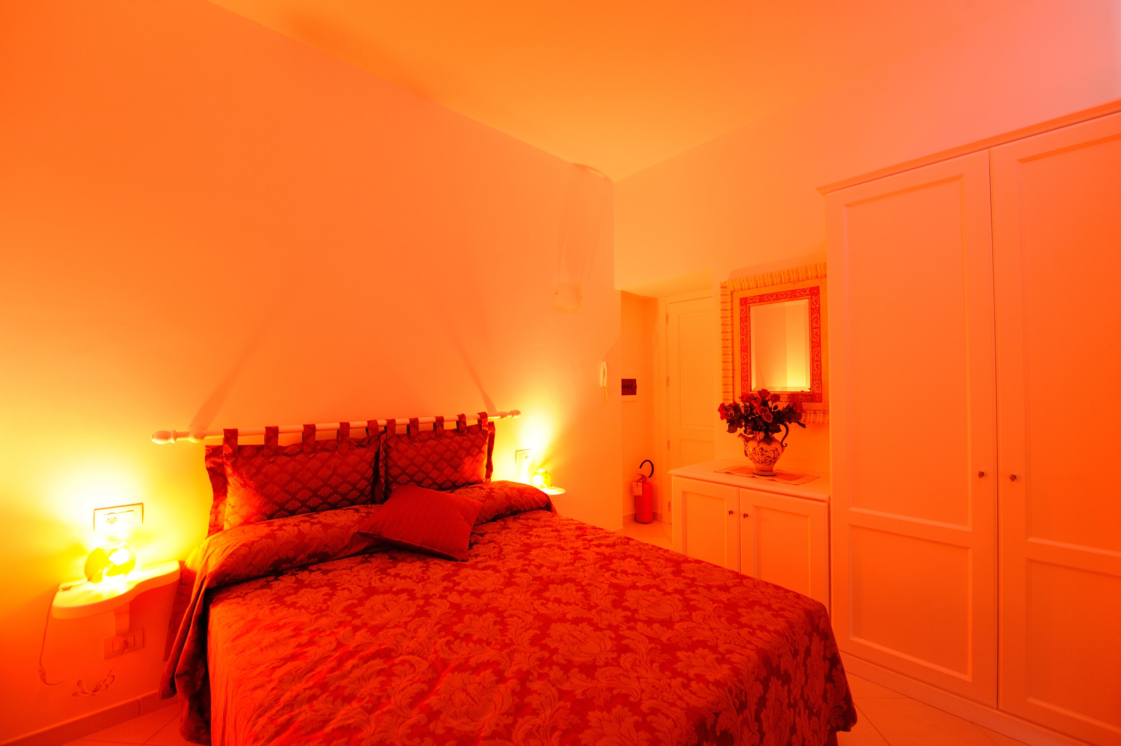 Un dormitorio con cama, mesitas de noche, cómoda y espejo.
