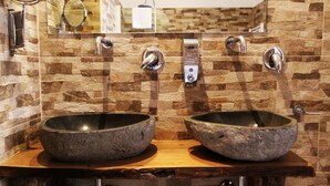 Un baño con dos lavamanos de piedra, un espejo y un perchero para toallas.