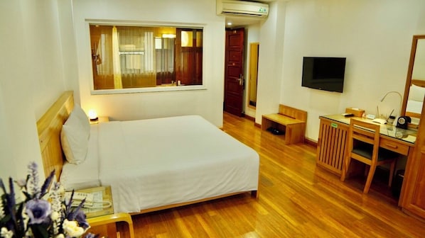 A hotel room with a bed, a desk, a TV, and a mirror.