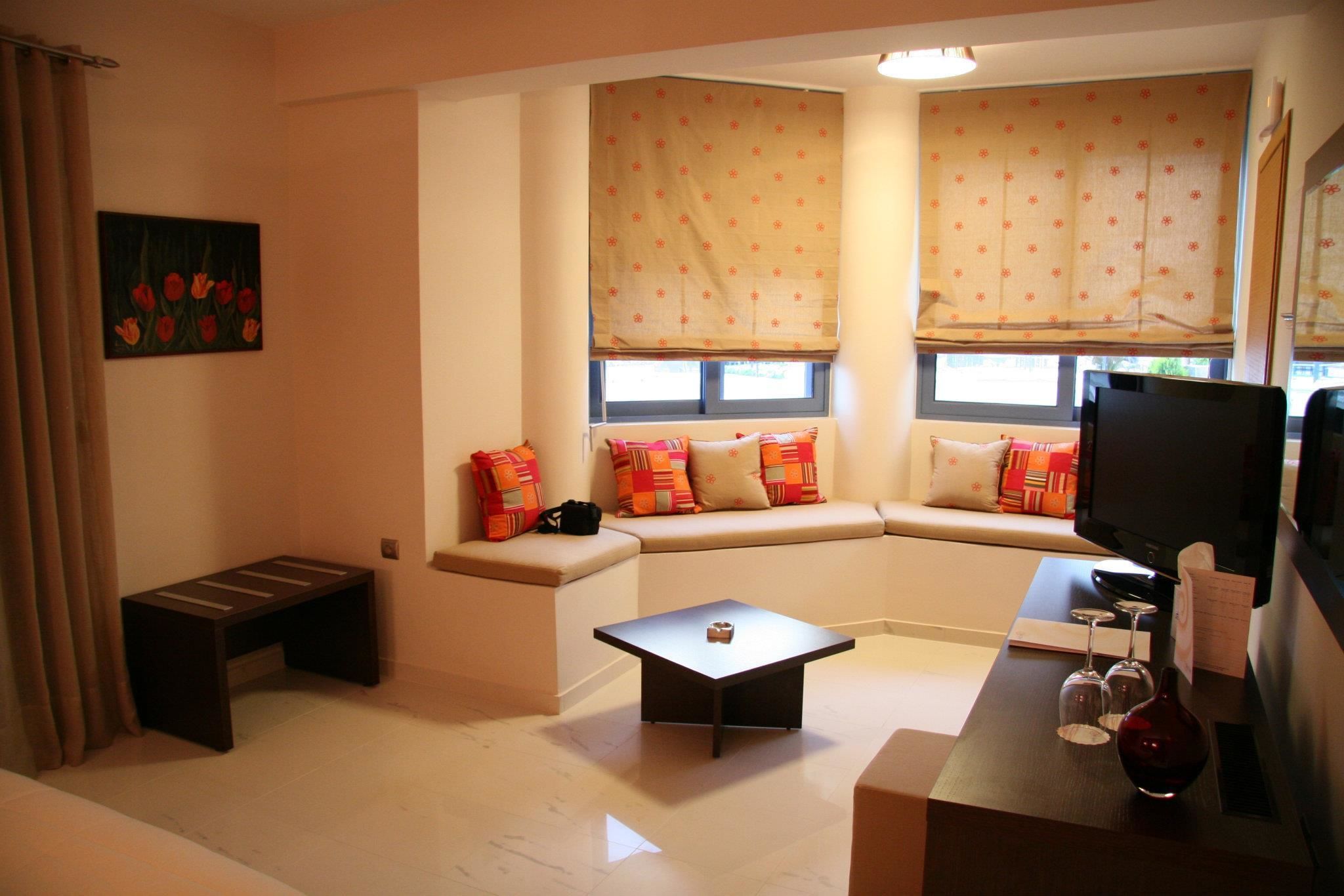 A living room with a sofa, a coffee table, a TV, and a window with a curtain.