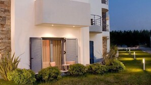 A modern two-story building with a flat roof, a balcony on the upper floor, and a small outdoor seating area with a table and chairs. - Sea Sight Hotel (Markopoulo Mesogaias)
