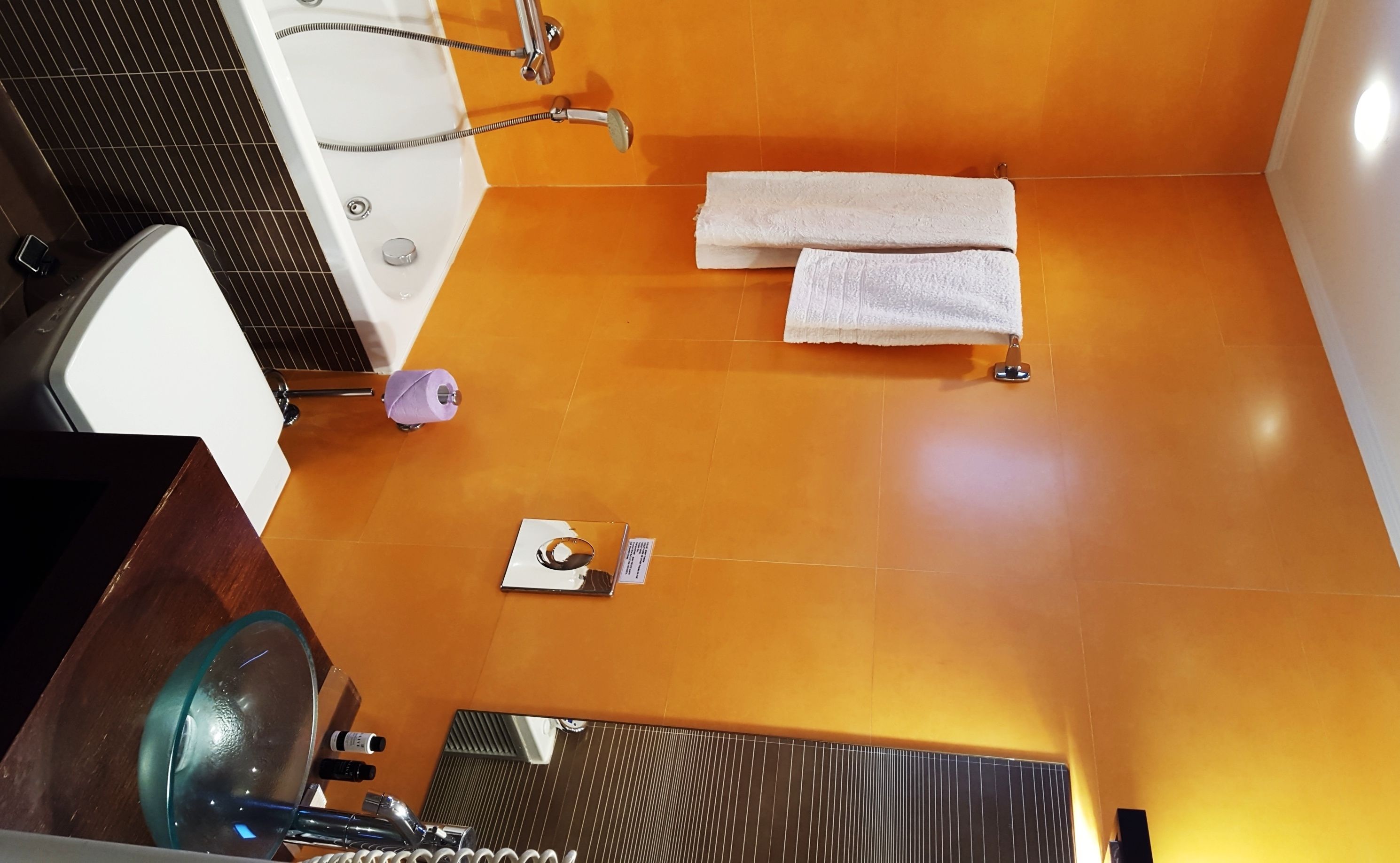 Een badkamer met een bad, een glazen douchecabine, een handdoekrek met twee handdoeken en een kleine spiegel.