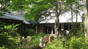 A garden with a pathway leading to a building with large windows and a brick facade.