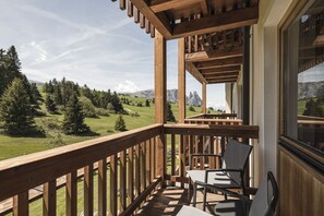 Un balcón de madera con vistas a un paisaje verde y montañas.