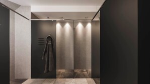 Un baño moderno con una paleta de colores oscuros, una toalla colgada en un perchero y suelo de baldosas.