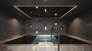 Un spa moderno con dos jacuzzis, una escalera central e iluminación empotrada.