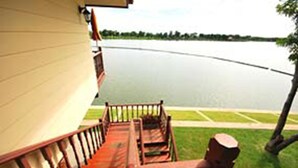 Una terraza de madera con barandilla que da a un lago tranquilo.