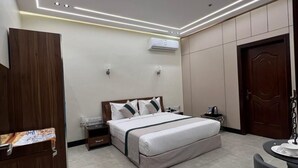 Ein modernes Hotelzimmer mit einem großen Bett, Nachttischen, einer Klimaanlage, einem Kleiderschrank und einem kleinen runden Tisch mit einem Stuhl.