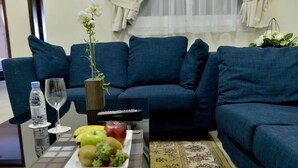 Ein Wohnzimmer mit einer Couch, einem Couchtisch mit Früchten und einer Vase sowie einer Fernbedienung.