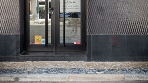 La entrada a un hotel boutique con un diseño moderno, que presenta una puerta de cristal y un cartel con el nombre del hotel y su horario de atención.