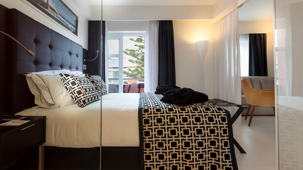 Habitación de hotel moderna con una cama grande, un escritorio y vistas al exterior.