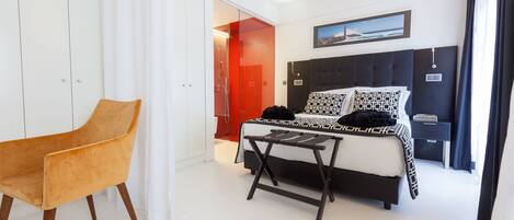 Un dormitorio moderno con cama, una silla y una mesita.