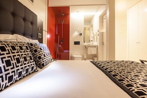 A hotel room with a large bed, a red door leading to the bathroom, and a white wardrobe. - Faro Boutique Hotel (Faro)