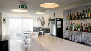 Zona de bar con mostrador de mármol, vasos transparentes y una variedad de botellas de licor.