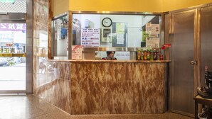 A reception desk with a marble counter, a clock, and various informational signs. - Good Hotel (Taichung)