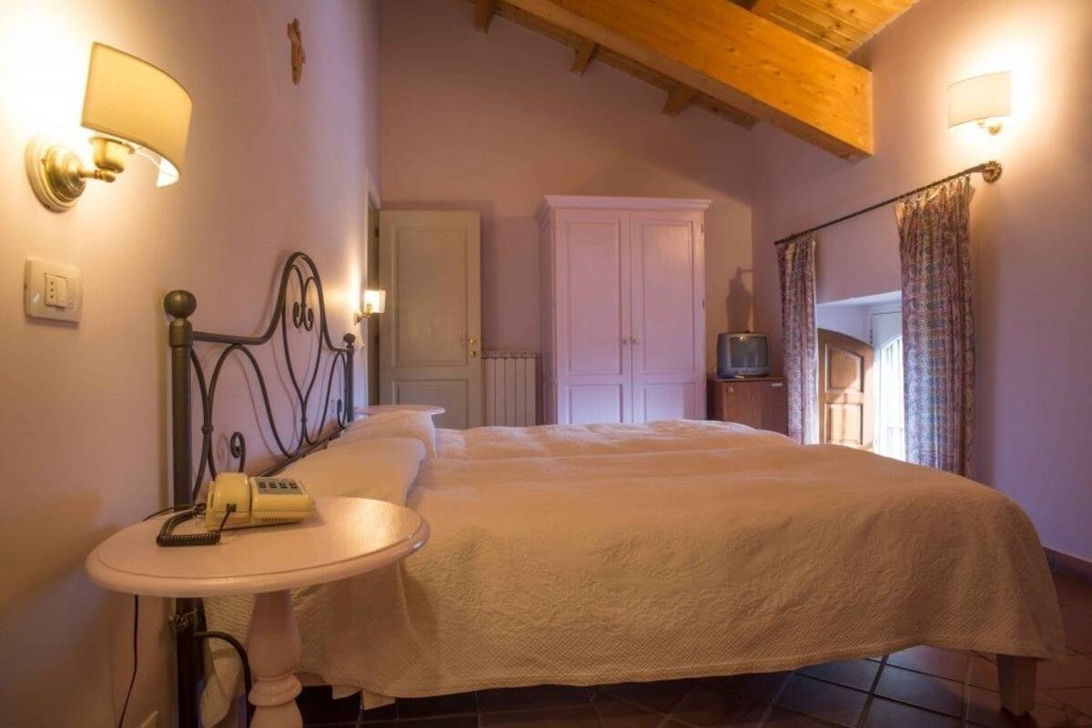 A bedroom with a bed, bedside table, lamp, wardrobe, and curtains.