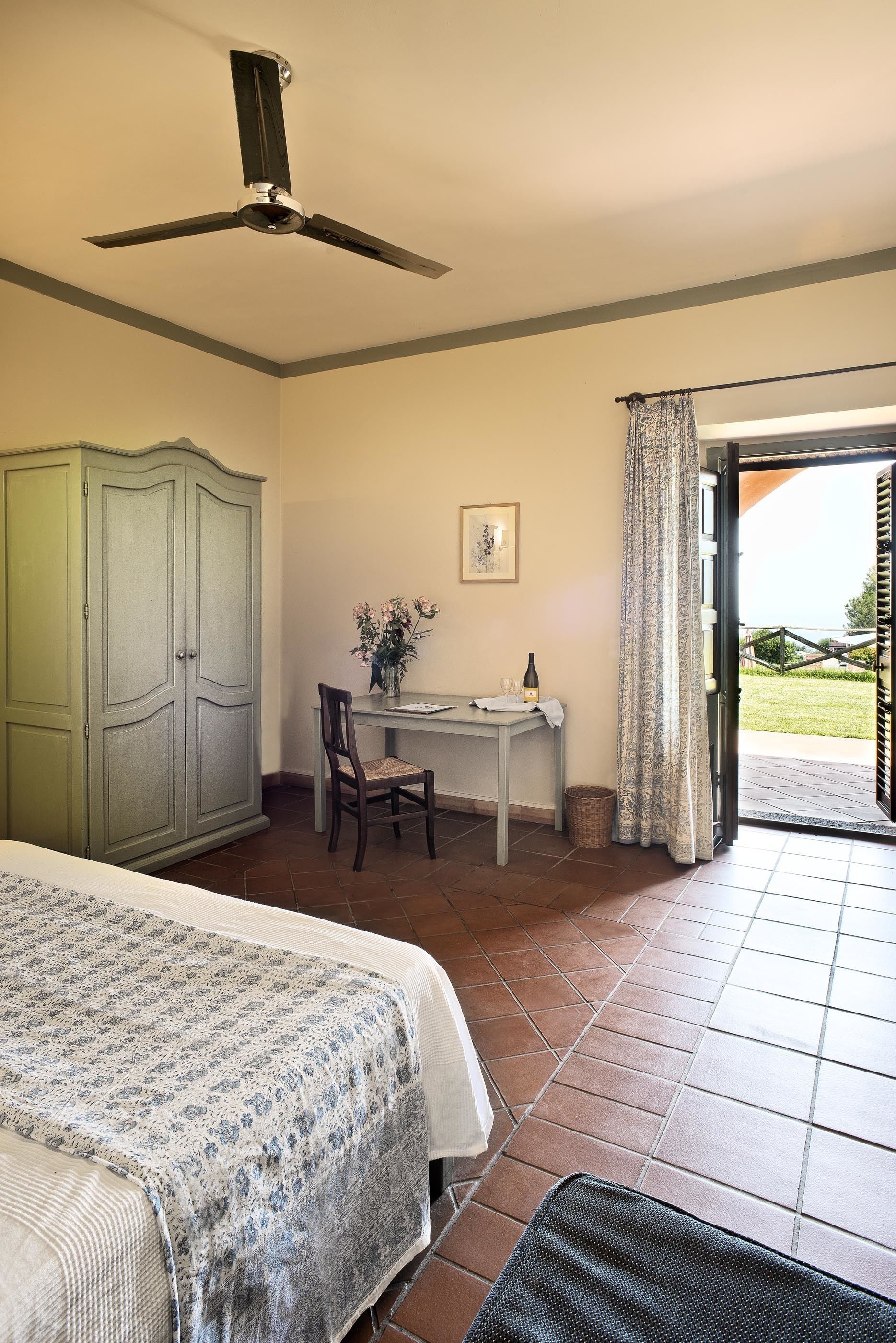 Un dormitorio con cama, escritorio, silla, armario y vista a través de una puerta abierta.
