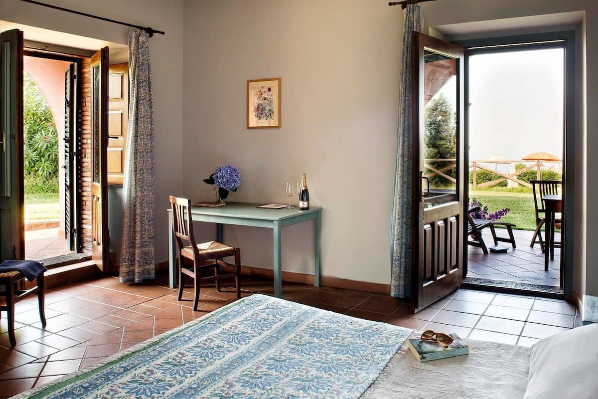 A bedroom with a large bed, a desk, and a view of the outdoors.