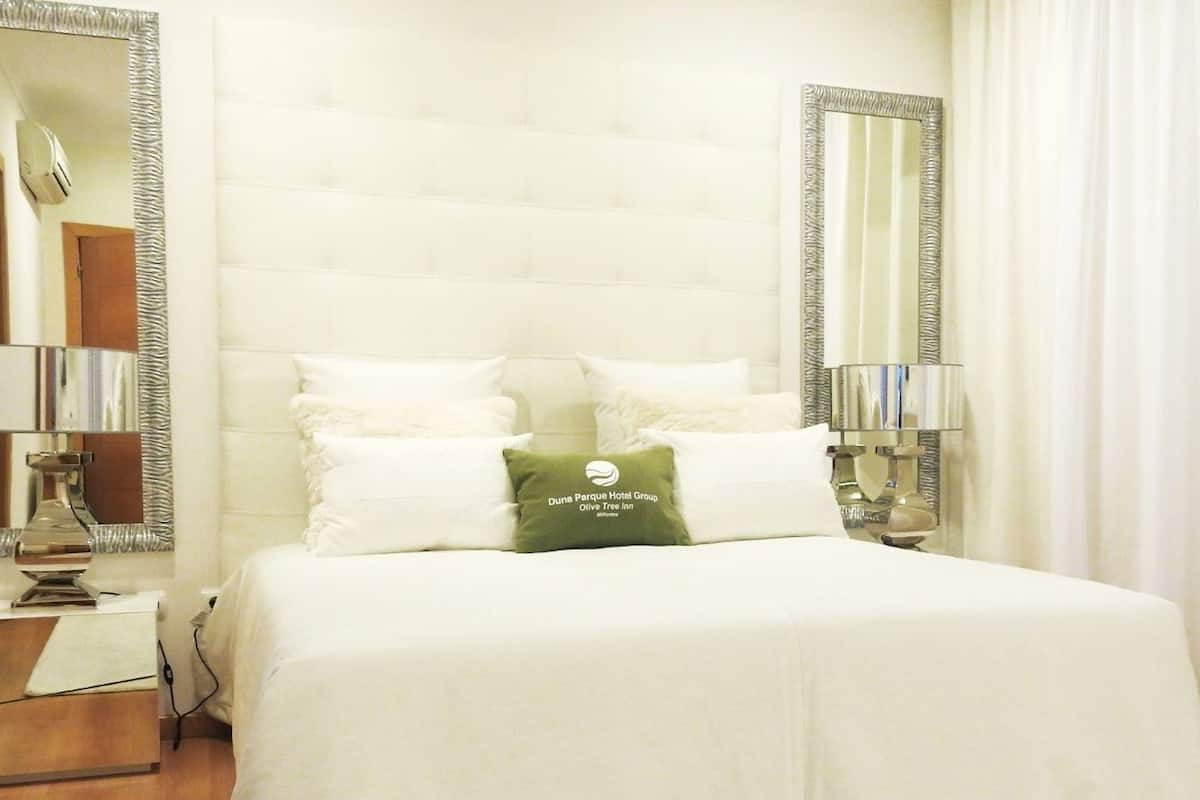A hotel room with a large bed, two nightstands, a mirror, and a pillow with the hotel's logo.