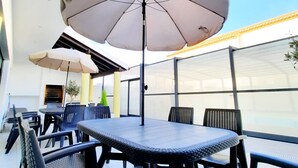 Een buitenzitplaats met tafels en stoelen, beschaduwd door parasols, met uitzicht op de lucht.
