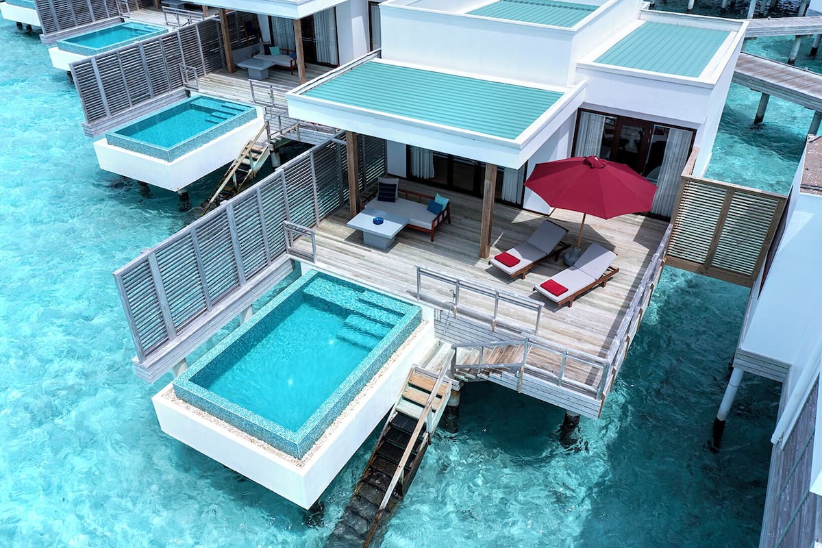 An overwater villa with a private pool, lounge area, and ocean view.