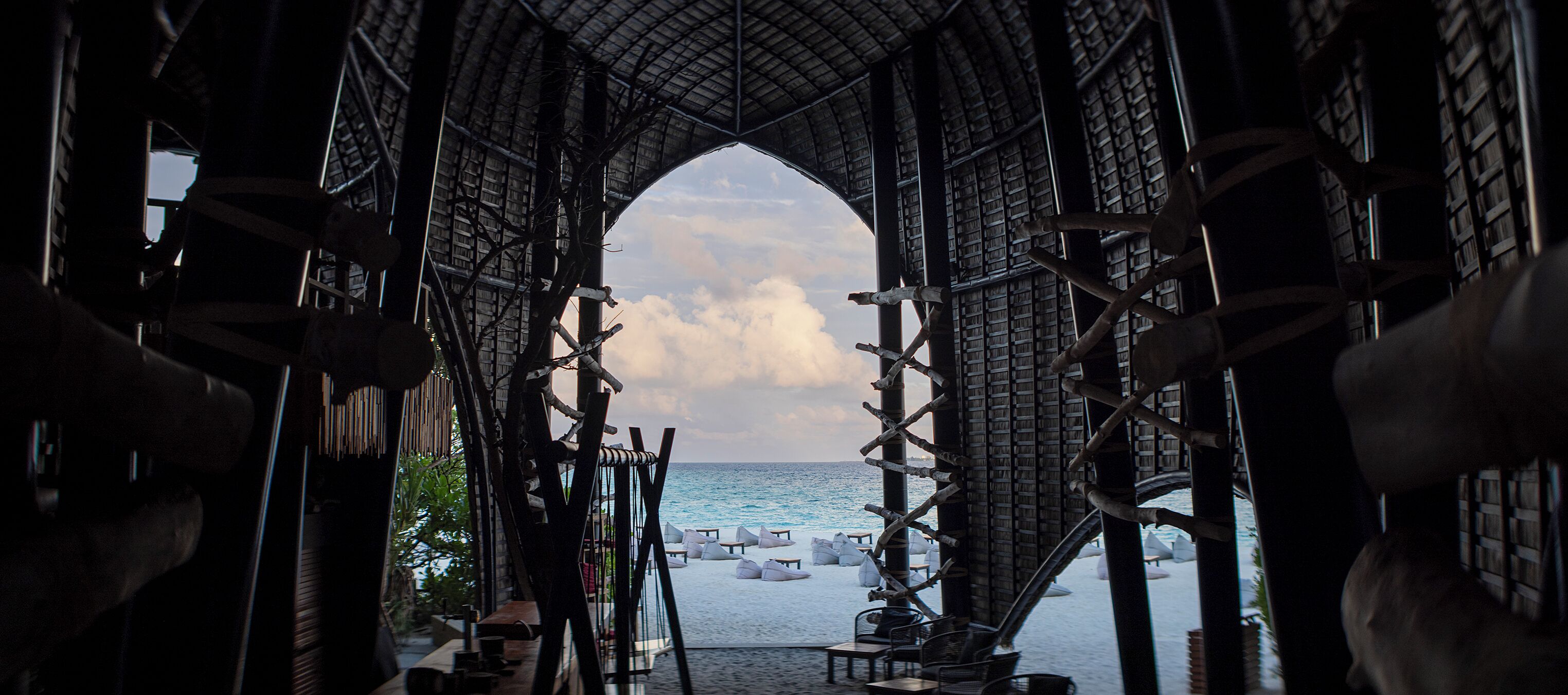 Una estructura arqueada con vista al mar y sillas de playa.