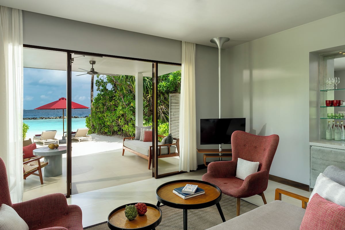 A modern living room with a TV, comfortable seating, and a view of the ocean.