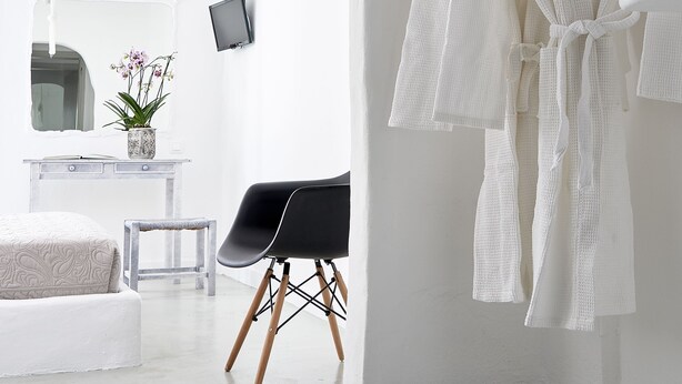 A minimalist bathroom with a white bathtub, a towel rack, and a mirror. - Milos Hotel (Milos)