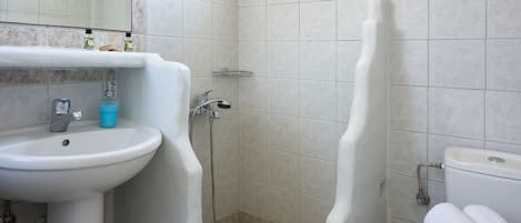 Un baño con lavamanos, espejo, ducha e inodoro.