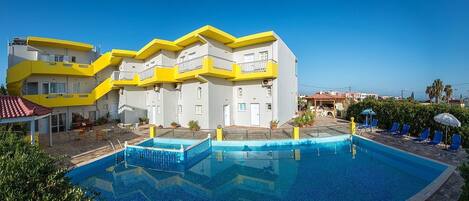 A hotel with a pool area, multiple balconies, and outdoor seating.