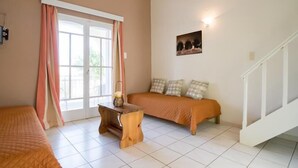 A bedroom with a bed, a nightstand, a window with curtains, a wall-mounted picture, and a staircase. - Kamaria Apartments (Hersonissos)