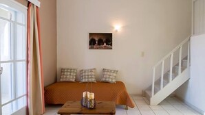 A bedroom with a bed, a bedside table with candles, a wall-mounted picture, and a staircase. - Kamaria Apartments (Hersonissos)