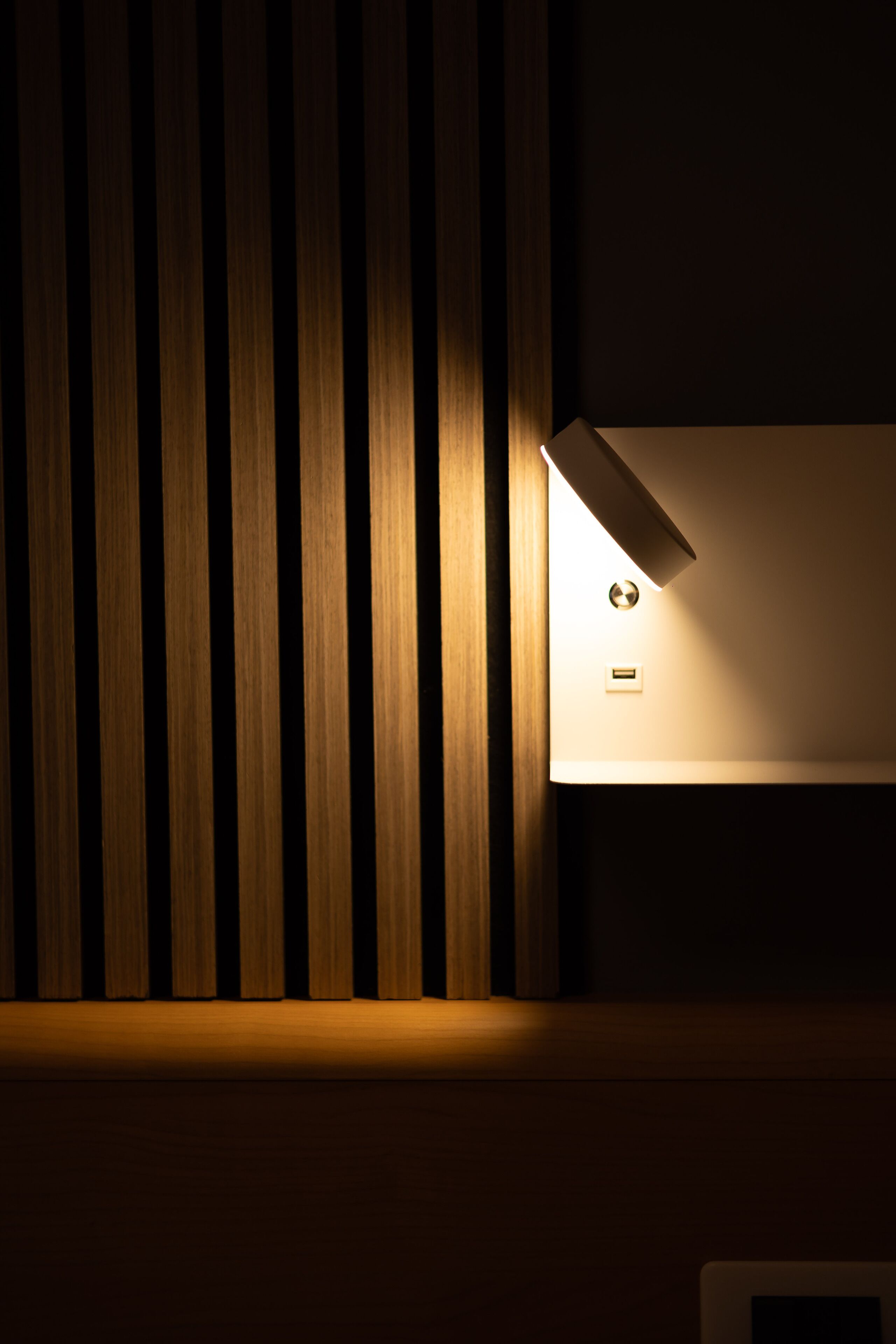 A wall with vertical wooden slats and a recessed wall-mounted light fixture.