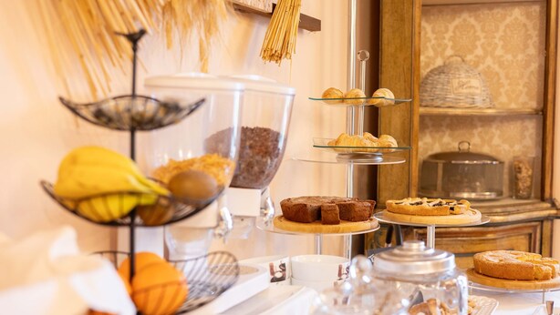 A buffet with various baked goods and pastries displayed on multiple tiers. - La Fertè Hotel (Asti)