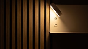 A modern interior with vertical wooden slats and a recessed wall-mounted light fixture. - La Fertè Hotel (Asti)