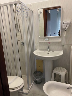 Ein Badezimmer mit Dusche, Toilette, Waschbecken und Spiegel.