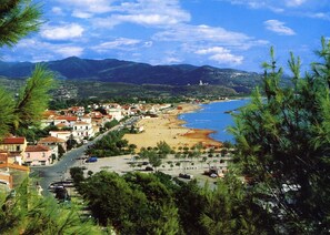 Eine Küstenstadt mit Strand, Gebäuden und Bergen im Hintergrund.