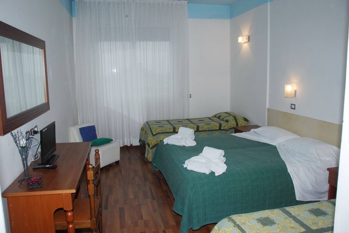 A hotel room with two beds, a desk with a computer, and a chair.