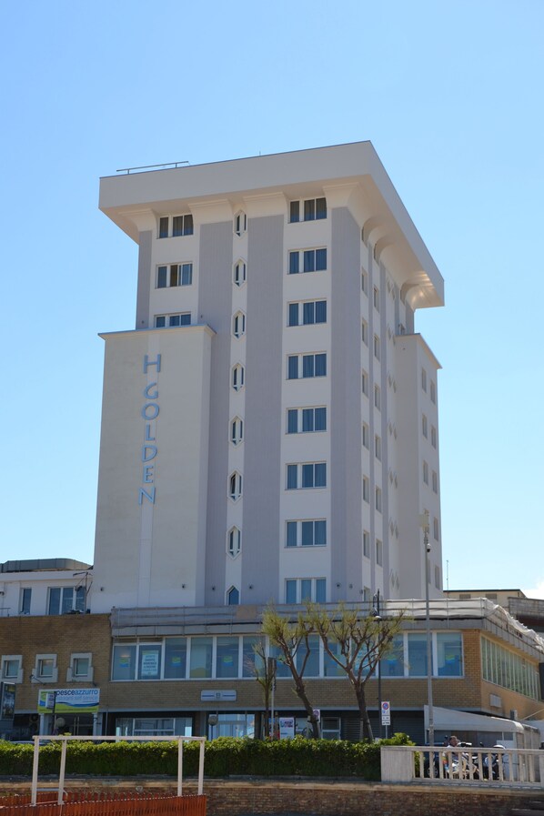 Un hotel moderno y alto con un llamativo letrero que dice "H GOLDEN" en la fachada.