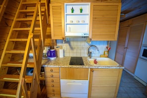Una cocina compacta con armarios de madera, lavavajillas integrado, un lavamanos y una pequeña encimera.